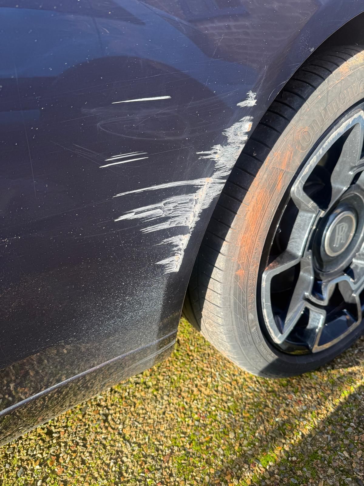 Dark luxury saloon rear quarter with deep white scuffs before repair